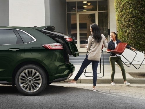 2024 Ford Edge view of woman using the power liftgate to load barstools in the cargo area